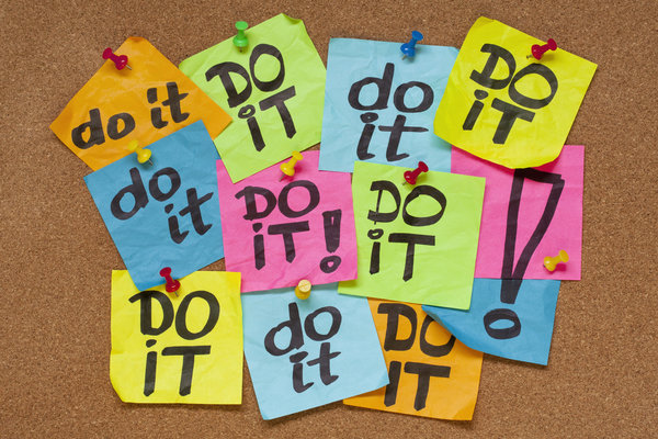 fighting procrastination concept - do it phrase on color sticky notes posted on a cork bulletin board